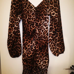 Leopardmönstrad klänning - Superfin klänning med ballong armar. Använd 1 gång. Normal i storleken. Passar perfekt till halloween om man vill klä ut sig till en leopard. 