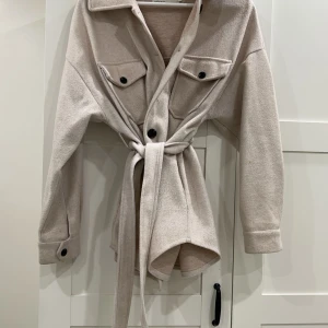 En mysig höstig kappa. Använd några gånger endast, bra skick på kappan. Mitt pris 250kr.  - Kappan är i storlek 34, beige. Lite oversized. 