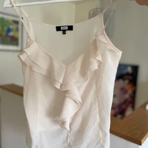 Vit volangtopp från Bik Bok - Säljer en superfin vit topp från Bik Bok i storlek S. Den har tunna axelband och vacker volangdetalj framtill. Perfekt för sommardagar eller festliga tillfällen. Toppen är i ett lätt och luftigt material som känns skönt mot huden.
