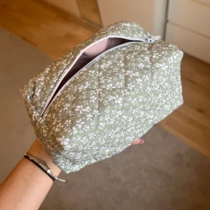 Grön blommig necessär - Egensydd necessär i grönt med vita blommor. Den är quiltad och har en praktisk dragkedja upptill!❣️