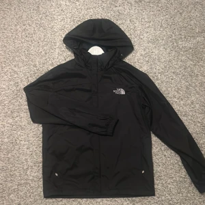 North face jacka - Säljer en svart vindjacka från The North Face Summit Series. Jackan har en justerbar huva och dragkedja framtill. Perfekt för blåsiga dagar och outdoor-äventyr. Skriv för minsta frågor eller funderingar. 