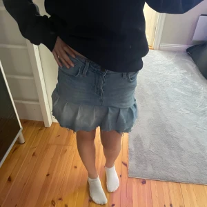 Jättefin lågmidjad jeanskjol med volang - Snygg lågmidjad jeanskjol med volangdetalj som jag sytt själv av ett par gamla lee jeans. Kjolen har en klassisk blå denimfärg, kort i modellen och den är perfekt till sommaren. Den har fickor både fram och bak samt en knapp- och dragkedjestängning.  Midjemåttet är 73 cm. 