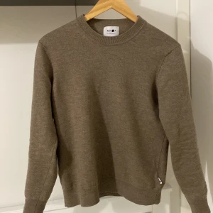 Brun tröja från NN07 - Säljer en stilren brun tröja från NN07. Tröjan är tillverkad av italienskt garn och har en klassisk rund halsringning. Perfekt för en avslappnad och snygg look. Om ni har frågor eller prisförslag är det bara att skicka in!