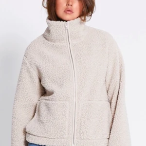 Beige teddyjacka🙌🏼 - Mysig teddyjacka i beige med dragkedja framtill. Jackan har en hög krage och långa ärmar, perfekt för kyliga dagar. Den har en avslappnad passform och är tillverkad i ett mjukt material som ger en skön känsla. Bestellde en i S och en i XS så säljer den som jag inte behåller!🩷