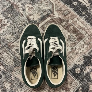 Gröna sneakers från Vans - Säljer ett par gröna Vans sneakers med vit sula och snörning. Skorna har den klassiska sidostripen i vitt och är perfekta för en avslappnad stil.