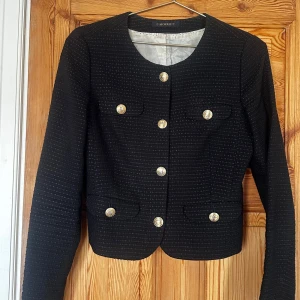 Svart kavaj från Morris - Elegant svart kavaj från Morris med guldknappar. Kavajen har en klassisk design med rund hals och långa ärmar. Perfekt för en stilren look.