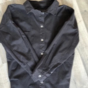 Svart overshirt - Säljer en stilren svart overshirt med knappar.