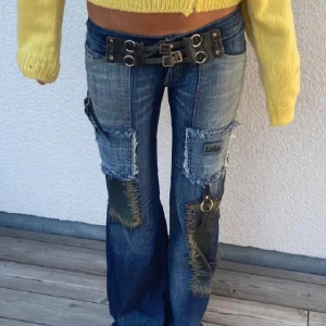 Blå jeans med patchar och bälte - Unika blå jeans med coola patchar och ett svart bälte med metallspännen. Jeansen har en bootcut-stil 
