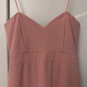 Rosa balklänning med släp - Elegant rosa långklänning med smala axelband och v-ringad hals. En jättefin balklänning med litet släp där bak. Ljusrosa färg ( lite svårt att se på bilderna) privat för bilder på 🌸🌸💕 använd en gång 