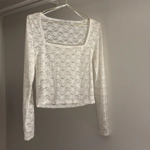 Vit spetsblus från MNG - Säljer en elegant vit spetsblus från MNG med långärmad design. Blusen har ett vackert blommigt mönster och en fyrkantig halsringning. Perfekt för att lägga till en romantisk touch till din outfit.