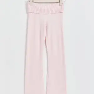 Mysiga ljusrosa stickade byxor med låg midja och bootcut-stil. 