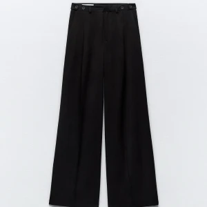 Svarta kostymbyxor från Zara - Snygga svarta kostymbyxor från Zara med hög midja och vida ben. Säljer på grund av att ja glömt skicka tillbaka och valde ett annat par. Helt nya och har legat i påsen hela tiden. Nypris 399