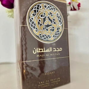 Majd Al Sultan Eau de Parfum från Asdaaf - Upptäck Majd Al Sultan, en Eau de Parfum för män från Asdaaf. Denna doft kombinerar rika toner av amber, rökig och träig med varma kryddor och balsamiska inslag. Flaskan har en elegant design med ett intrikat mönster och en gyllene kork. Perfekt för den som söker en djup och sofistikerad doftupplevelse.