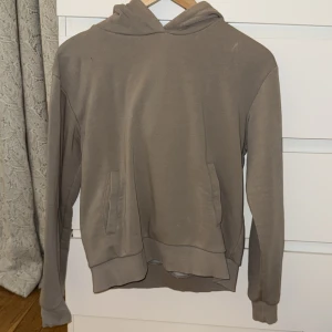 Beige hoodie från NA-KD - Säljer en stilren beige hoodie från NA-KD. Den har en klassisk design med huva och fickor framtill. Perfekt för en avslappnad look.