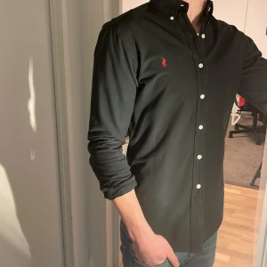 Ralph Lauren Skjorta - Tja säljer en Ralph lauren skjorta i färgen svart och i storlek S passar 170-180 cm ungefär. Nypris 1295 KR mitt pris 299 KR. Inga defekter som hål eller fläckar. Skriv vid frågor eller funderingar.