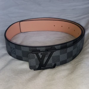 Rutig bälte med mönster. - Snyggt bälte med klassiskt rutigt mönster i svart och grått. Perfekt för att ge din outfit en fin touch.