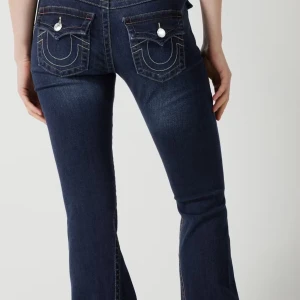 True religion joey Low Rise flare jeans  - Snygga mörkblå Low Rise jeans ifrån True Religion med fickor på baksidan. Säljer dessa pågrund av att storleken inte passade mig vid midjan. Har användts fåtal gånger. Finns små slitningar nertill vid vänstra sidan. 