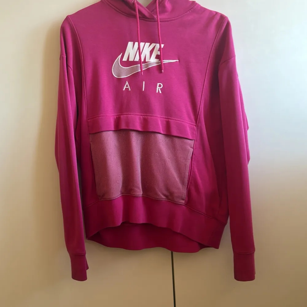 Säljer en rosa hoodie från Nike med deras klassiska logga i vitt på framsidan. Hoodien har en stor ficka framtill och justerbar huva med dragsko. Perfekt för en avslappnad stil.. Neuletakit & Villapaidat.