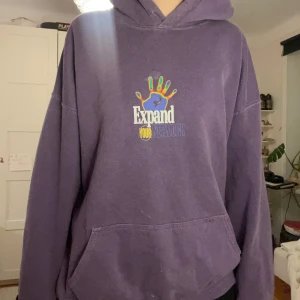 Lila hoodie med tryck - Säljer en lila hoodie med färgglatt tryck på både fram- och baksidan. Hoodien har en stor ficka framtill och en bekväm passform. 