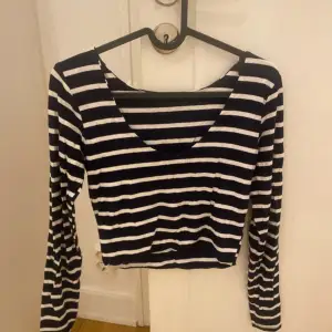 Säljer en snygg randig topp i svart och vit med långa ärmar. Toppen har en v-ringad design och är perfekt för en avslappnad stil. Den är tillverkad i ett mjukt och bekvämt material.