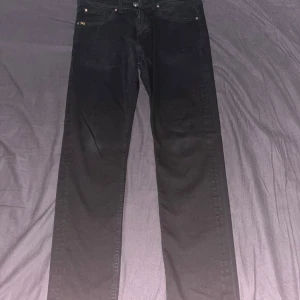 Svarta jeansbyxor - Snygga svarta jeansbyxor med klassisk design. De har en rak passform och är perfekta för en stilren look. Byxorna har knappar och dragkedja framtill samt fickor både fram och bak.