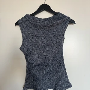 Mörkblå snedaxel topp - Oanvänd mörkblå topp med en snedskuren axel och texturerad yta.