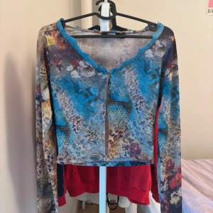 Flerfärgad topp från Jaded London - såå nice topp från Jaded London med ett unikt mönster och blå spetsdetaljer. varit välanvänd och älskad hos mig!! den går att stänga med 4 krokar, ena har tyvärr ramlat av (se bild 3) men det går att fixa om man e pysslig