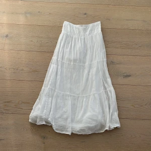 Vit långkjol från Gina Tricot - Säljer en vacker vit långkjol från Gina Tricot. Kjolen har en elastisk midja och ett luftigt fall som ger en skön och avslappnad känsla. Perfekt för varma dagar och kan enkelt matchas med olika toppar. 🌼