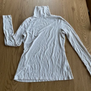 Vit ribbad polotröja - Superskön polo-tröja från HM. Strl S men lite åtsittande passform. Finns ett yttepyttelitet hål vid axeln, se bild. 