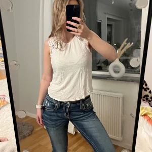 Vit topp med spets - Säljer en söt vit ärmlös topp med spetsdetaljer vid axlarna🤍
