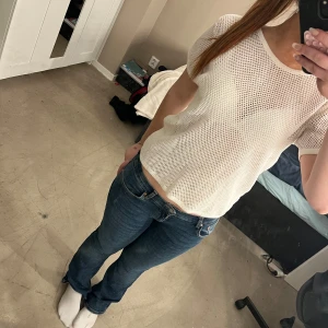 Vit nätmönstrad topp - Säljer en vit nätmönstrad topp med korta ärmar. Perfekt för en avslappnad stil. Toppen har en luftig design och är lätt att matcha med olika outfits.