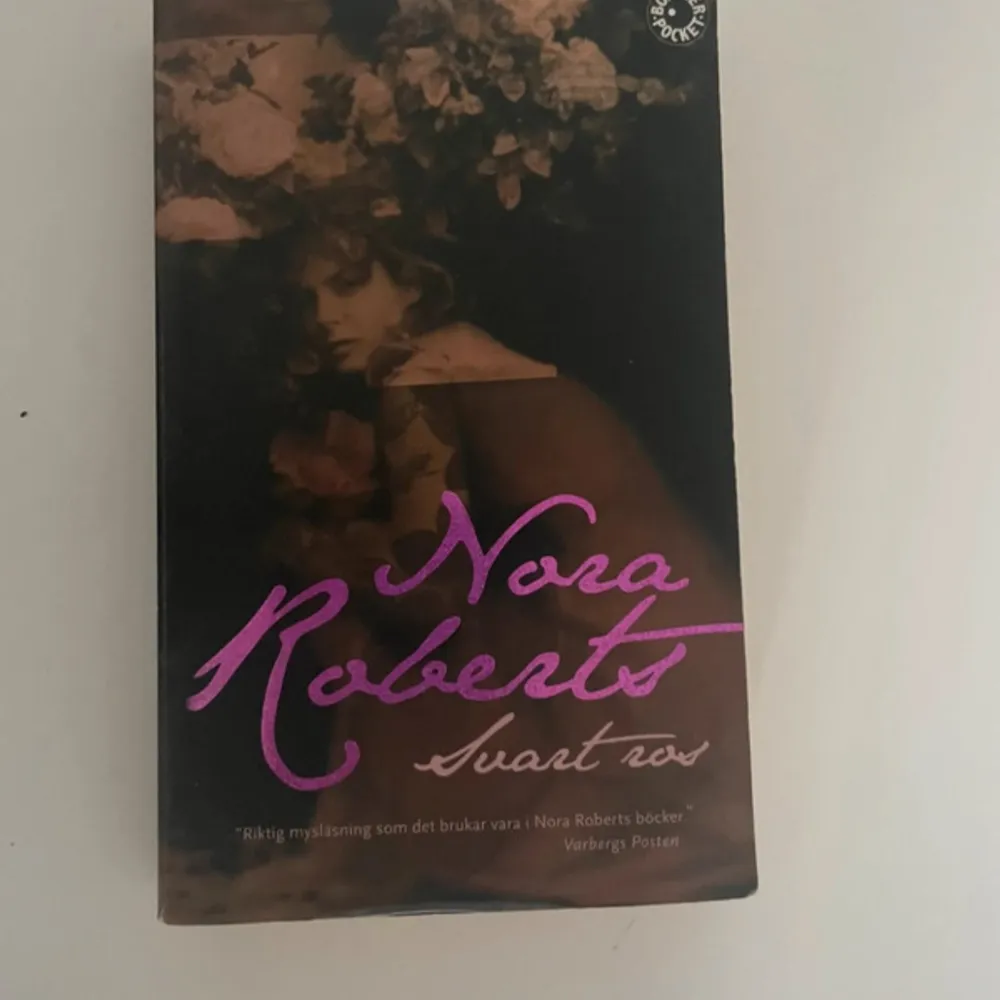 Boken 'Svart ros' av Nora Roberts är en del av en trilogi som handlar om starka kvinnor och deras livsöden. Den följer Rosalind 'Roz' Harper som kämpar med att övervinna sitt förflutna och hitta kärleken igen. En berättelse fylld av mystik, romantik och familjehemligheter.. Böcker.