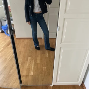 Svart mockajacka med fuskpäls - Snygg svart mockajacka med fuskpälsdetaljer och dragkedjor. Jackan har en cool bikerstil med snedställd dragkedja och två framfickor med dragkedja. Perfekt för att ge din outfit en edgy touch.