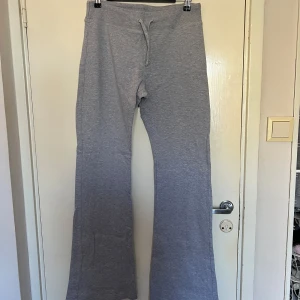 Lågmidjade grå mjukisbyxor från Brandy Melville - Säljer ett par grå mjukisbyxor från Brandy Melville. Byxorna har en bekväm passform med dragsko i midjan för justerbarhet. Perfekta för en avslappnad stil.