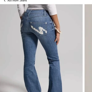 Blå bootcut jeans med mönstrade bakfickor - Snygga blå bootcut jeans med unika mönstrade bakfickor. De har en klassisk femficksdesign och en knappgylf. Perfekta för en avslappnad stil med en twist. Använda 1 gång❣️ nypris 699kr