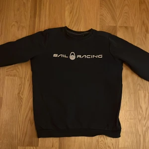 Svart tröja från Sail Racing - Säljer en mörkblå tröja från Sail Racing i storleken 160. Texten är lite sliten men håller fortfarande sin kvalitet. Perfekt för en avslappnad stil. Fråga gärna om fler blider. Nypris 600kr.