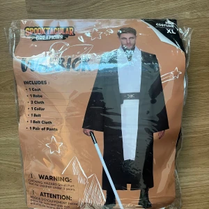 Svart och vit kostym från Spooktacular Creations - Säljer en svart och vit kostym från Spooktacular Creations. Setet inkluderar en kappa, en rock, en krage, ett bälte och ett par byxor. Perfekt för temafester eller Halloween!