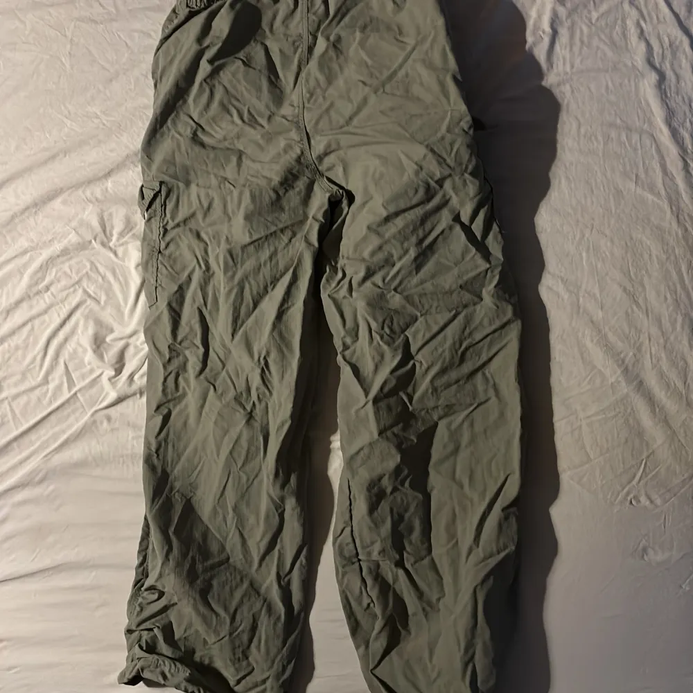 Säljer ett par gröna cargopants med praktiska fickor och snörning vid bensluten och även vid midjan. Byxorna har en loose passform och är perfekta för en avslappnad stil. De är tillverkade i ett lätt och bekvämt material. . Farkut & Housut.