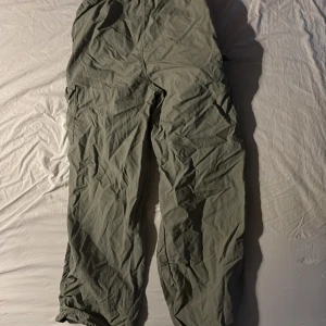 Gröna cargopants med snörning - Säljer ett par gröna cargopants med praktiska fickor och snörning vid bensluten och även vid midjan. Byxorna har en loose passform och är perfekta för en avslappnad stil. De är tillverkade i ett lätt och bekvämt material. 