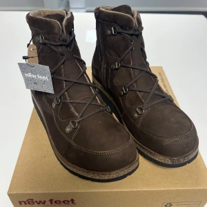 Bruna kängor från New Feet - Damkängor med snörning och blixtlås från New Feet. Yttersula EVA med medium rullfunktion. Avtagbar 6 mm stötdämpande soft innersula. Storlek 40. Helt nya med prislapp och i orginal kartong. Tillverkade i Danmark. Nypris 1950kr