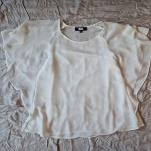 Vit blus från Bikbok  - Säljer en luftig vit blus från Bikbok.. Blusen har en lös passform med korta ärmar och är tillverkad i ett lätt och transparent material. Perfekt för varma dagar eller som ett stilrent lager över ett linne.