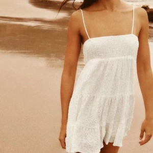 Zara strl L Vit sommarklänning med volanger - Säljer en söt cremevit sommarklänning med smala axelband och volangdetaljer. Klänningen har en luftig passform och är perfekt för varma dagar. Den är tillverkad i ett lätt och bekvämt material i bomulls-crepe. Strl L. Normal i storleken (har S på bilden, säljer denna åt en vän) 