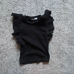 Svart volang tröja från Zara - Säljer en svart tröja ifrån Zara med volang i armarna! Använd ett par gånger men inga defekter! 