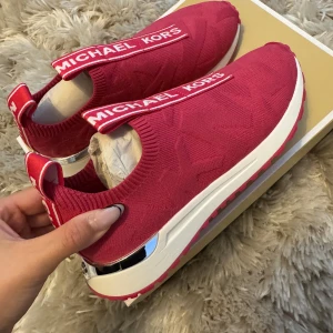  sneakers från Michael Kors - Snygga rosa sneakers från Michael Kors med vit sula och silverdetaljer.                                                      Helt nya!! Normal till lite stora i storleken (jag brukar vanligtvis ha 37) Skokartongen följer med om det önskas.