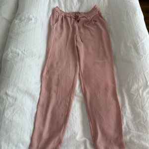 Rosa mjukisbyxor från Zara - Säljer ett par bekväma rosa mjukisbyxor från Zara Basic Collection. Byxorna har en elastisk midja med snörning för justerbar passform. Perfekta för en avslappnad stil.