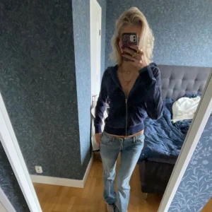 Mörkblå hoodie med dragkedja - Säljer en mörkblå hoodie med dragkedja och långa ärmar. Perfekt för en avslappnad stil. Den har en enkel design utan mönster och är gjord i ett mjukt material. Intorkad limfläck på baksida arm, skriv för bild.