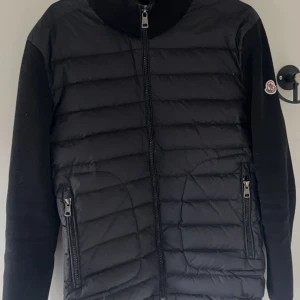 Svart moncler cardigan - Säljer en stilren svart cardigan jacka från Moncler. Jackan har långa ärmar och dragkedja framtill samt två praktiska fickor med dragkedjor. Perfekt för våren. S men passar xs