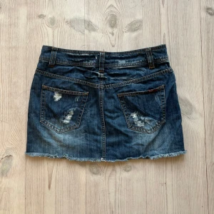 Blå lågmidjad jeanskjol  - Mörkblå lågmidjad jeanskjol från Only i fint skick. Kan inte hitta storlek men skulle säga S/M. Tvärs över midjan är det 39 cm och längs med sidan är det 33 cm. Använd gärna köp nu!