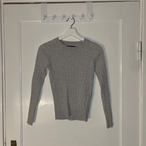 Grå ribbad tröja - Säljer en stilren grå ribbad tröja med långa ärmar. Perfekt för kyligare dagar och lätt att matcha med olika outfits.