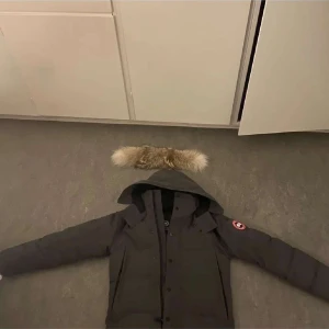 Canada goose wyndham parka (äkta) - Säljer en grå parkajacka från Canada Goose med avtagbar pälsdetalj på huvan. Jackan har långa ärmar och flera praktiska fickor. Perfekt för kalla dagar, och även halv kalla dagar. Priset är inte slaget i sten, byten med pengar eller bara rent av byten e också intressant.